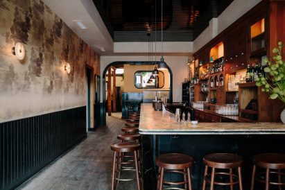 L-shaped bar with a marble counter and surrounded by wooden stools