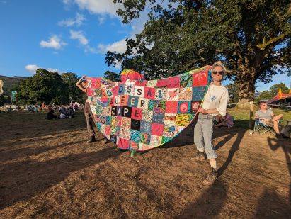People holding up a multicoloured cape