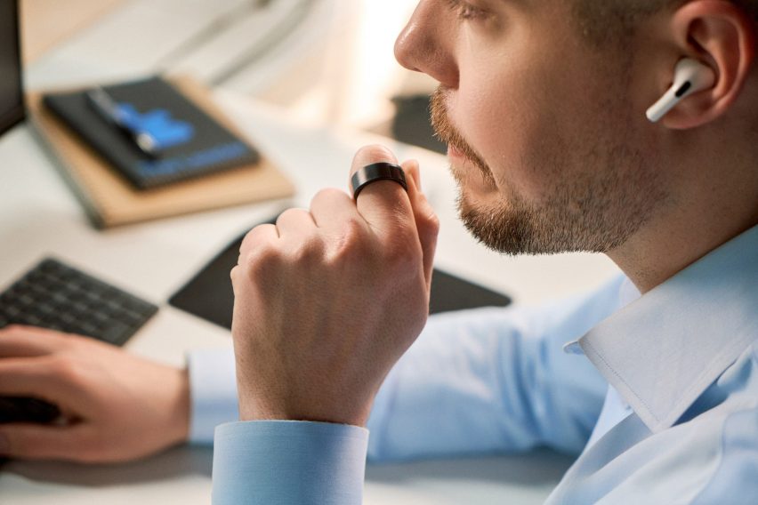 Photo of a man at his work desk speaking into his WIZPR ring