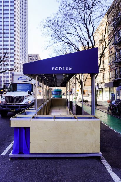 Pavilion with blue restaurant logo and skyscraper in the background