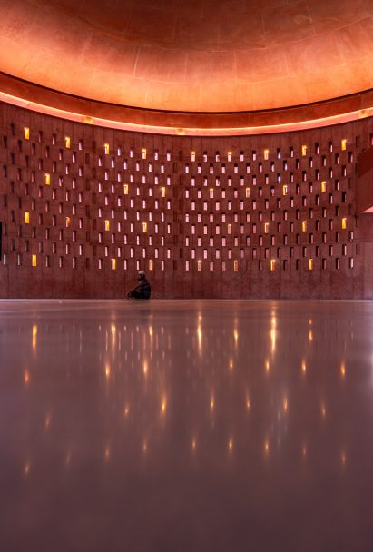 Worshipper sitting in the prayer hall of the Zebun Nessa Mosque by Studio Morphogenesis