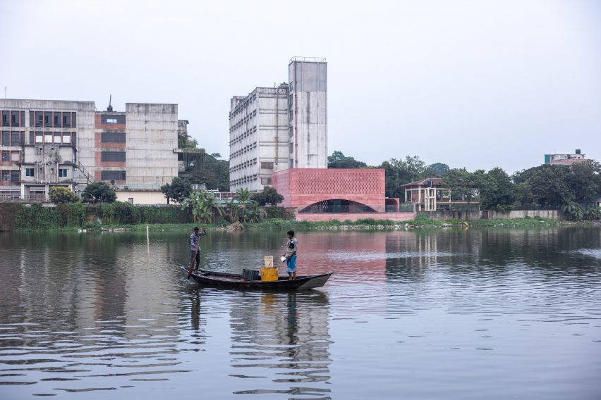 Two viewers in boats look across the water at Zebun Nessa Mosque by Studio Morphogenesis in Bangladesh