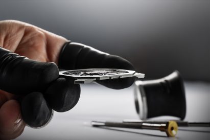 Fingers holding a watch face in construction