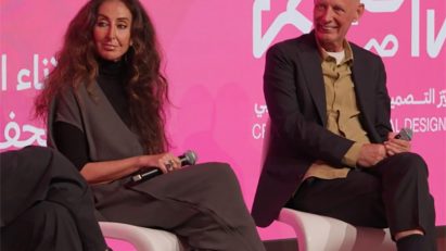 Video still of Manuela Lucà-Dazio and Ben van Berkel sitting on stage at a panel at the Design Doha Forum with a bright pink screen behind them