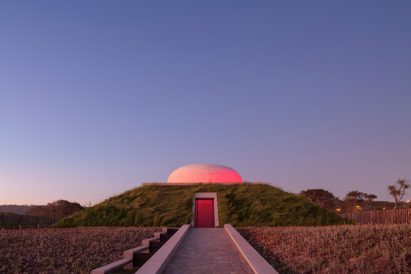 Trapezoid-shaped, grass-covered building with dome on top