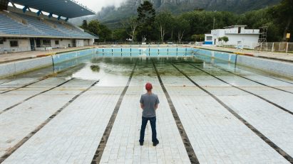 Photo of man standing in near-empty Newlands municipal swimming pool in Cape Town by Bloomberg via Getty Images