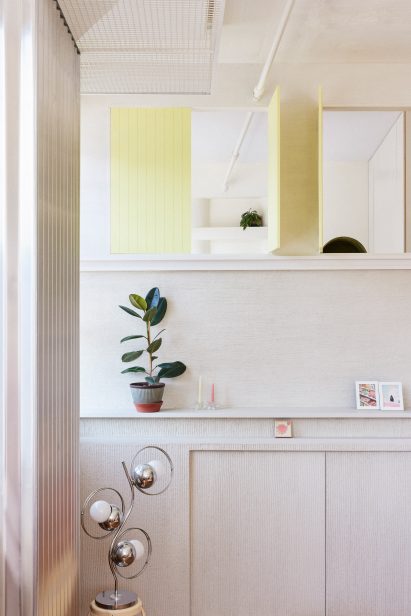 Pale yellow shutters partially open high in the wall