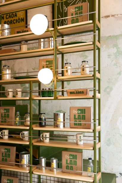 A green metal framework forms an open shelving system that partially conceals a staircase