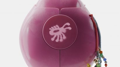 Product photo of a pink Terra device in the shape of a beetle or lady bug, with a little beaded tassel hanging off one side and a bug illustration on the front