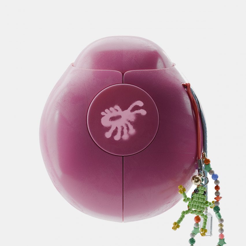 Product photo of a pink Terra device in the shape of a beetle or lady bug, with a little beaded tassel hanging off one side and a bug illustration on the front