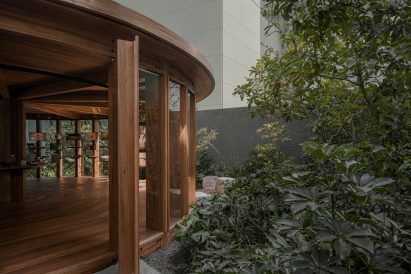 Entrance to wooden pavilion with plants surrounding