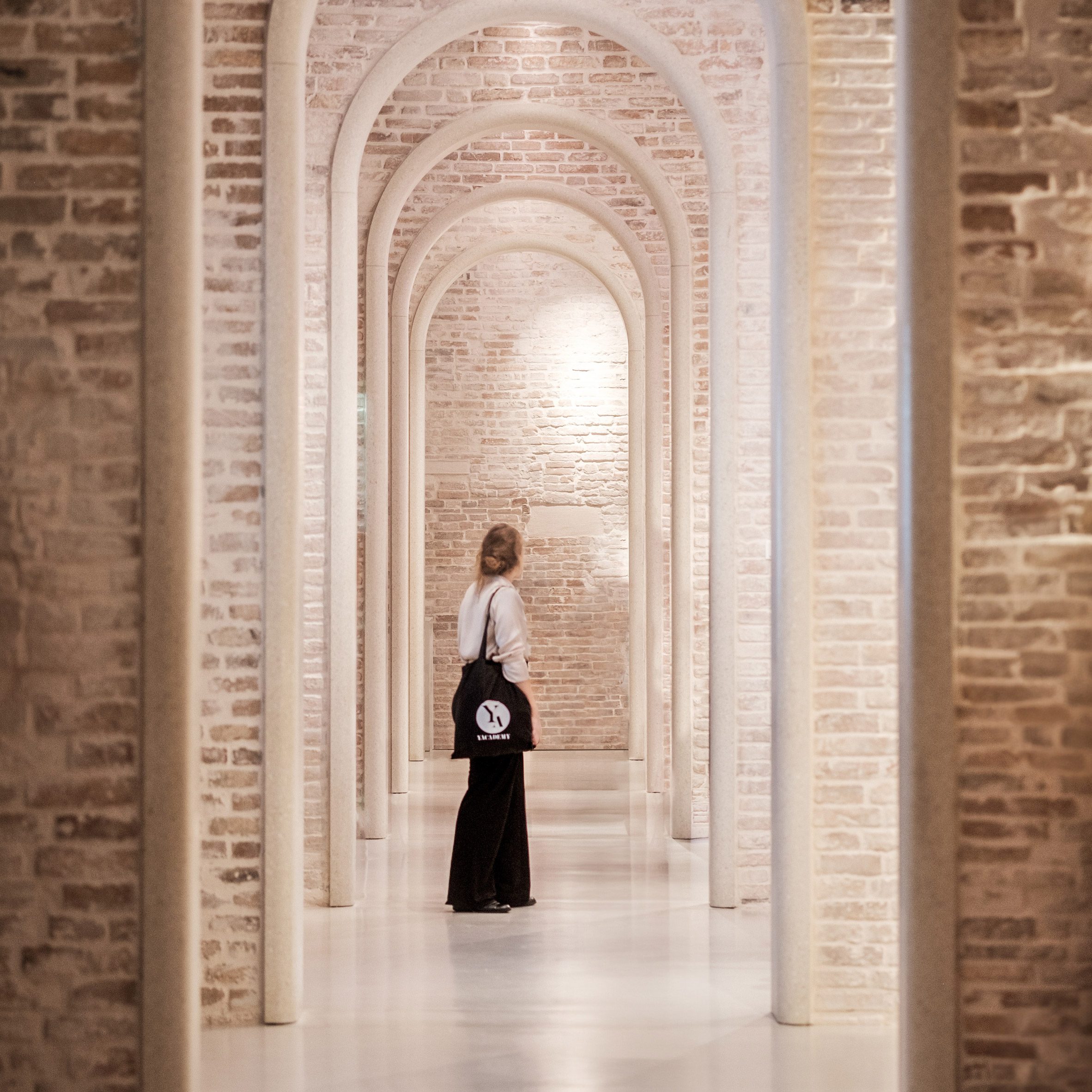 a person standing in a corridor surrounded by brick and stone