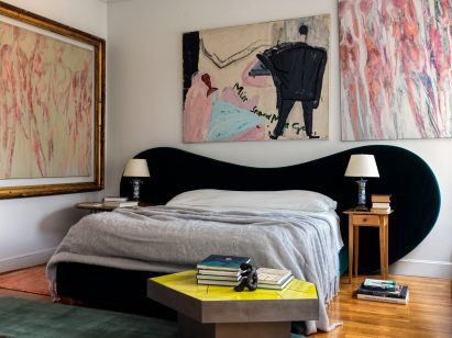 Bedroom with a curvaceous headboard wrapped in dark green velvet