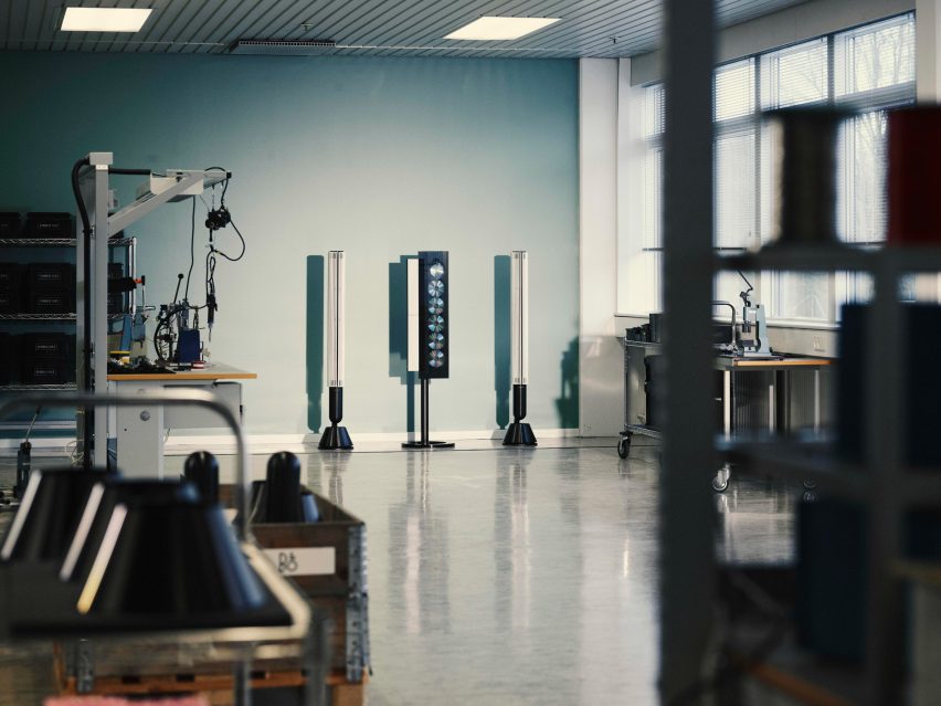 Photo of a restored and recoloured Beosound 9000 six-CD player stand-mounted vertically with a long speaker on either side, on display within a factory