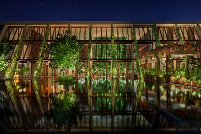 Building with louvred teak panels behind a large reflecting pool