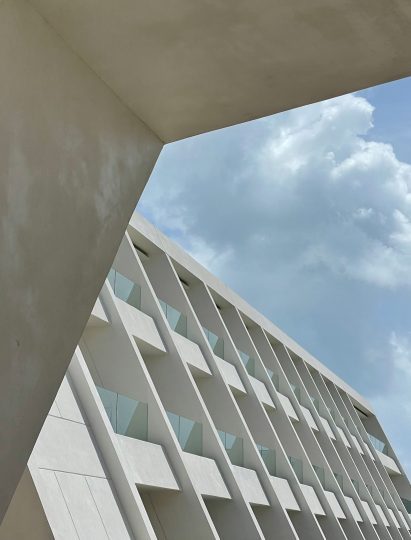 White angled building with three storeys of balconies