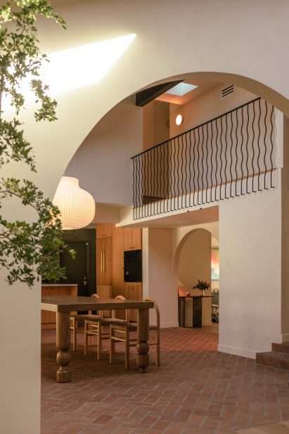 View through arched opening to mezzanine with wavy iron balusters