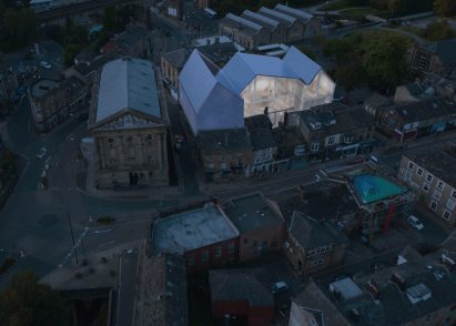An image showing a bird's eye view of a city, with a large white illuminated building.