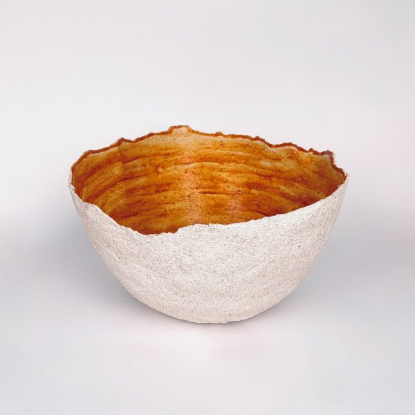 A irregularly shaped bowl, beige on the outside and orange on the inside.
