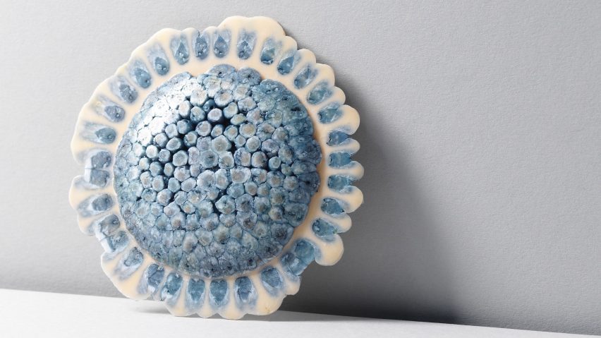 A circular jewellery piece in colours of blue and white against a white background.