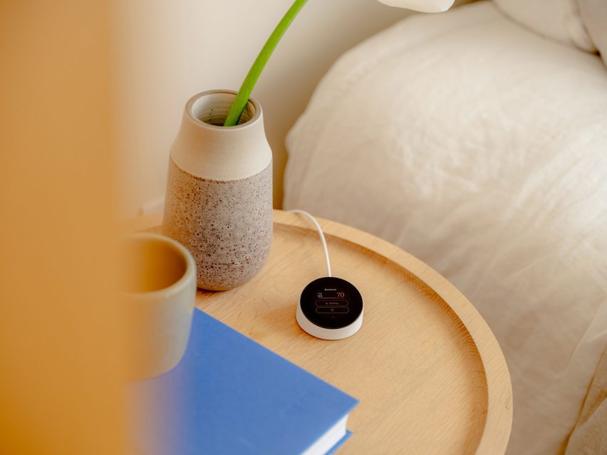 Photo of the Quilt Dial, a small circular device, sat on a wooden side table