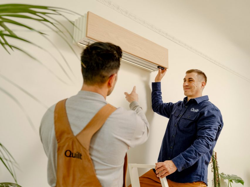 Photo of two men installing a Quilt climate control system on the wall of a room