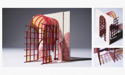An architectural model conveying stained glass details in colours of pink, blue and yellow, against a red brick wall.