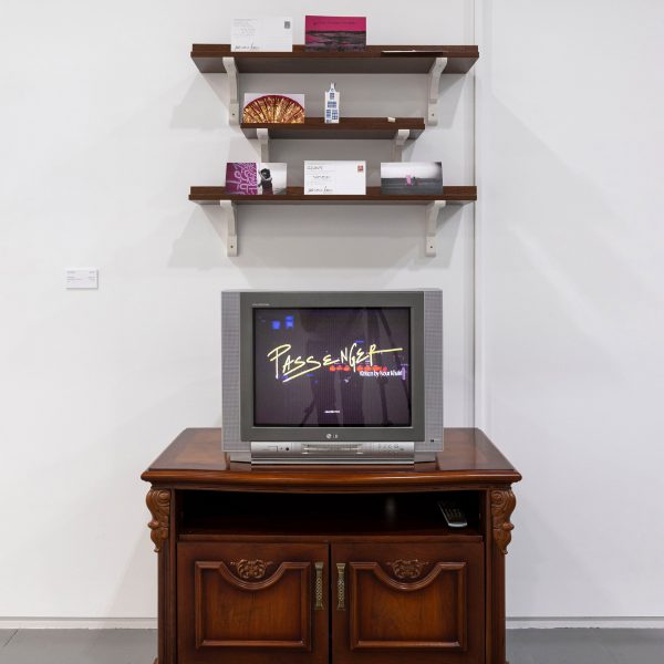 A photograph of a dark brown cabinet against a white wall with a television on top, with three dark brown shelves above.