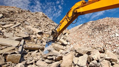 Construction and concrete demolition waste recycling site with excavator boom crusher