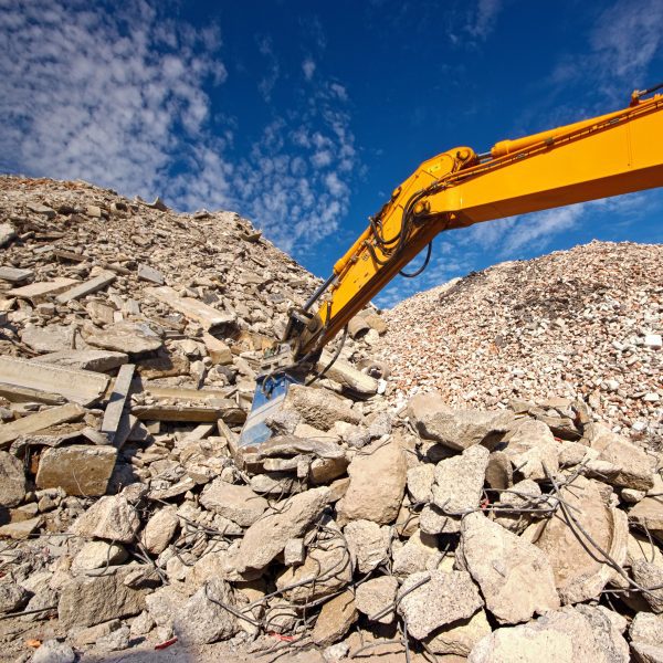 Construction and concrete demolition waste recycling site with excavator boom crusher