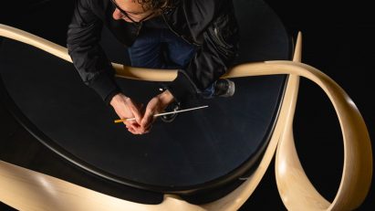Conductor Teddy Abrams leaning on conductor's rail designed by Joseph Walsh Studio