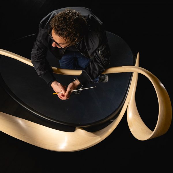 Conductor Teddy Abrams leaning on conductor's rail designed by Joseph Walsh Studio