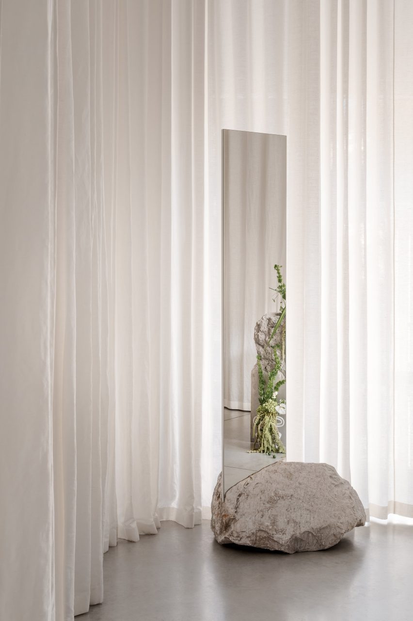 A mirror and rock in front of curtain