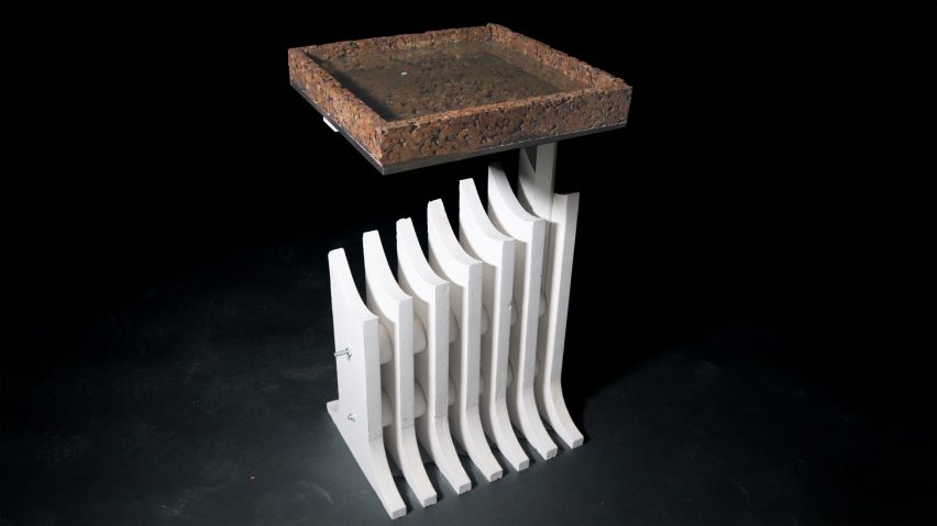 A side table with a square shaped cork tabletop and a diagonally shaped white base.