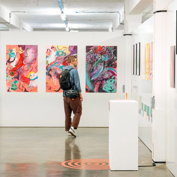 Photo of person looking at works at the UAL Awarding Body Origins Creatives exhibition