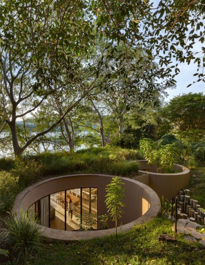 House with cylindrical voids embedded into a slope and disguised by a green roof