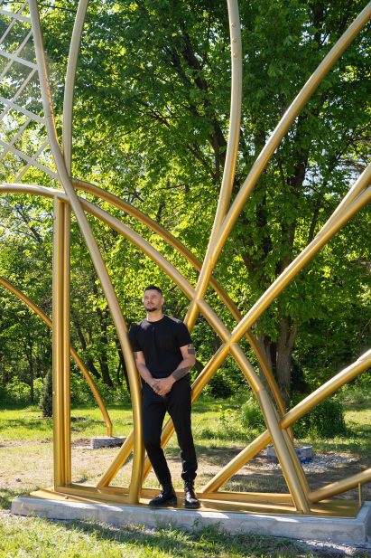 Jordan Weber standing with a gold-painted sculpture