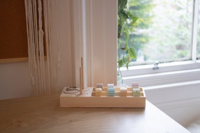 A photograph displaying a product on a table that aids people with ADHD, it features beige coloured wood and different colours of blue, yellow, pink and green.