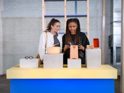 Promotional photo for Dundee Design Festival showing two women looking at objects on a display table