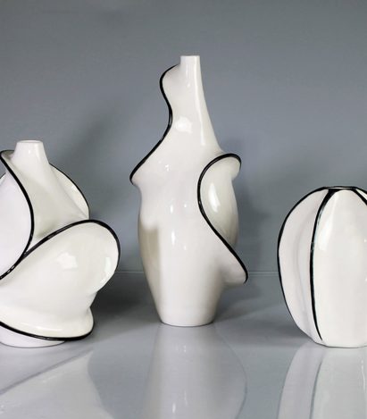 A photograph of three ceramic objects in colours of white and black, against a grey backdrop.