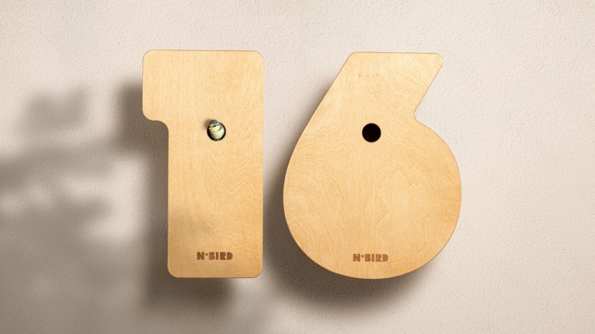 A photograph of two wooden bird boxes in the shapes of numbers one and six next to one another. The 'one' has a small bird inside, looking at the camera.