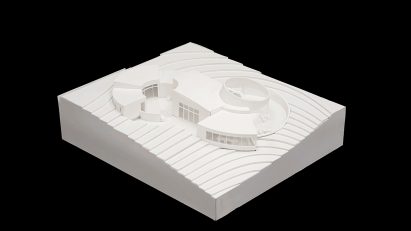 A photograph of a white architectural model against a black background.