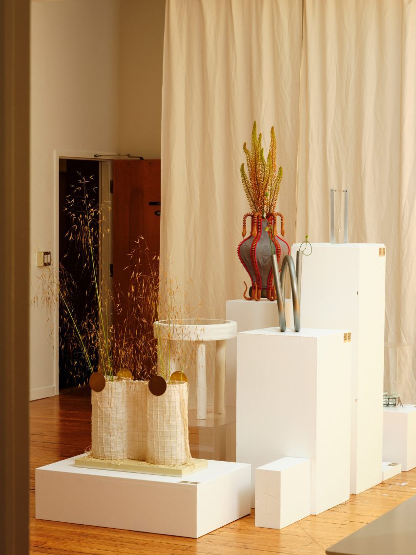 Objects on white pedestals in front of a curtain
