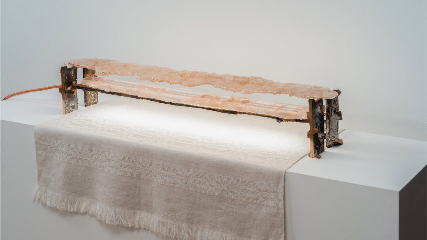 A photograph of a lighting installation featuring a structure in brown tones, with a piece of white fabric underneath.