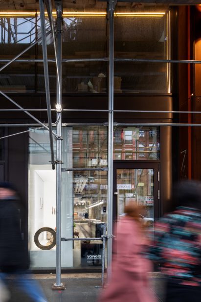 Showroom and exhibition space visible through a fully glazed facade, past scafolding