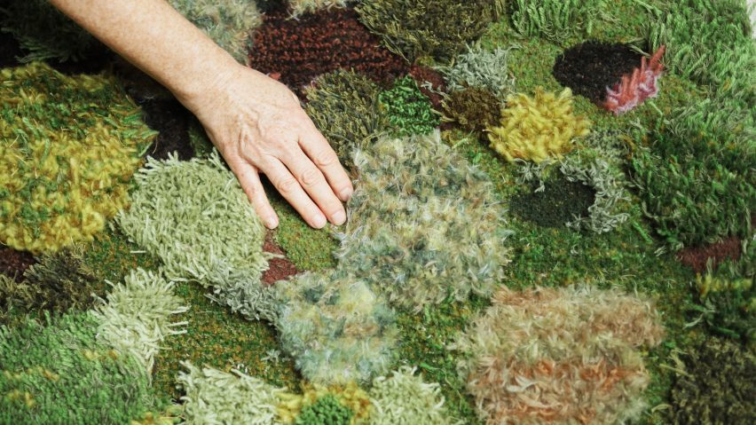 A photograph of a person's hand interacting with a multi-textured surface in colours of green, yellow and orange.