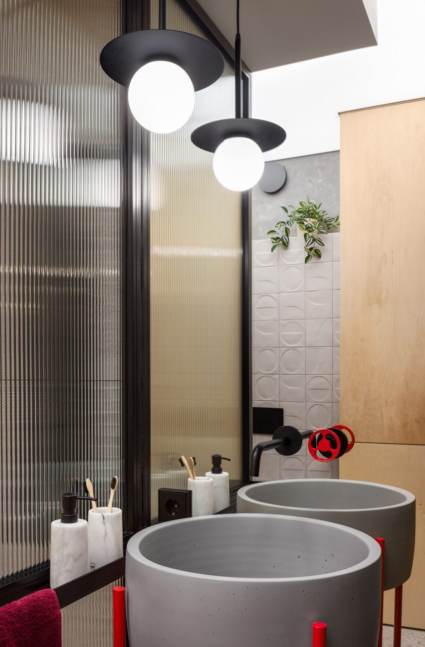 Grey basins with red legs and reeded glass panels in bathroom
