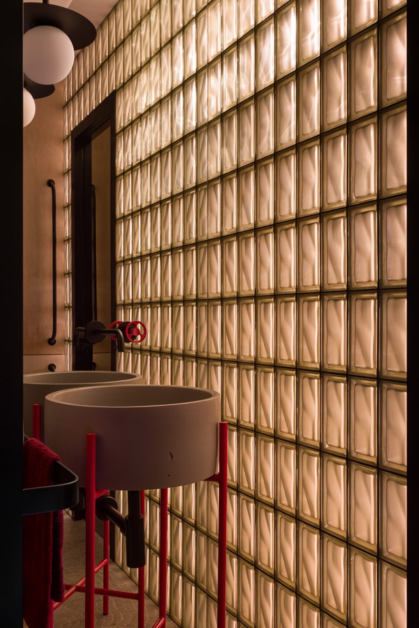 Glass bricks dividing bathroom and grey wash basin with red legs
