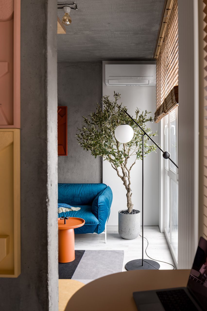 Blue sofa and orange coffee table in apartment by Dihome