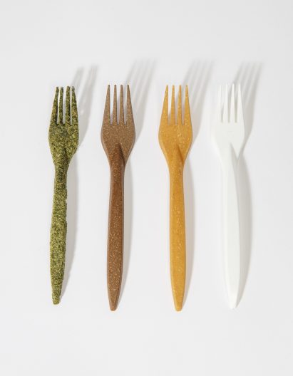 A photograph of four forks made using different natural materials, in tones of green, brown, yellow and white, against a grey background.
